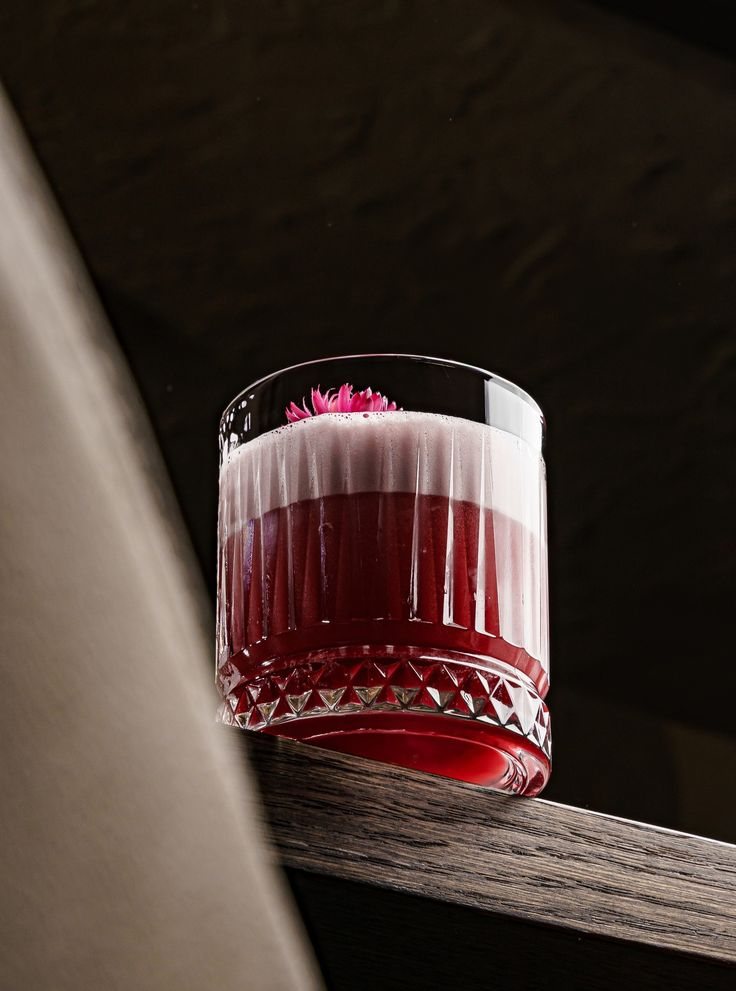 Un cocktail rosso con schiuma e fiore